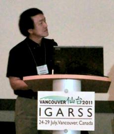 井上上席研究員の発表。手前のプレートには「VANCOUVER 仙台 2011 IGRASS」と書かれている（写真）